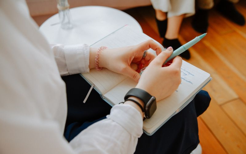 Therapist holding pen and notebook during CBT session.