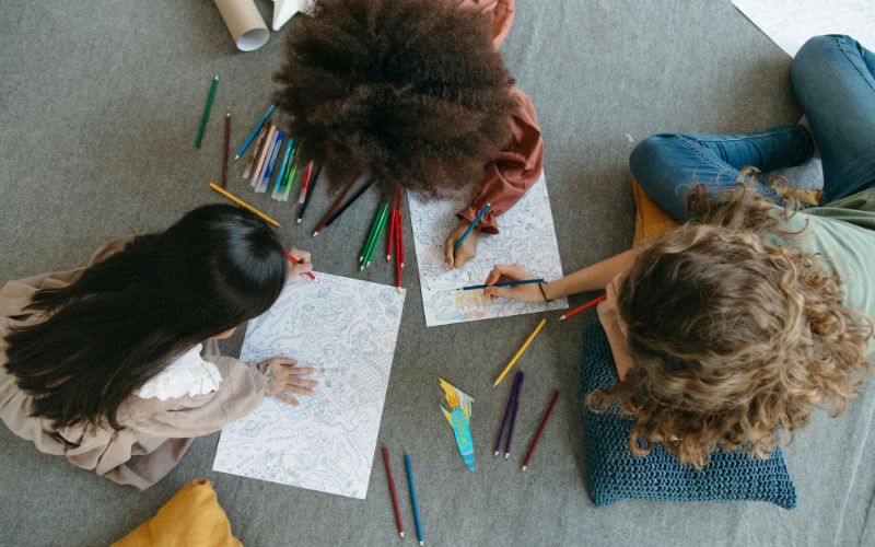 Children coloring with pencils during CBT therapy activity.