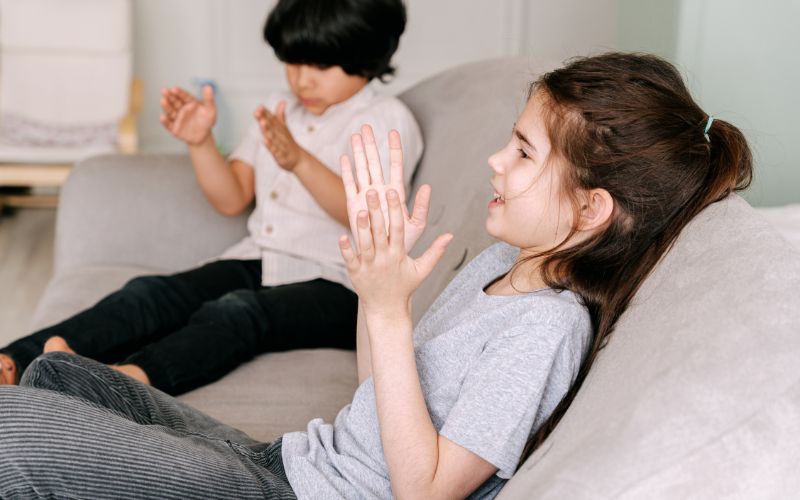 Children clapping hands during playful CBT therapy session.