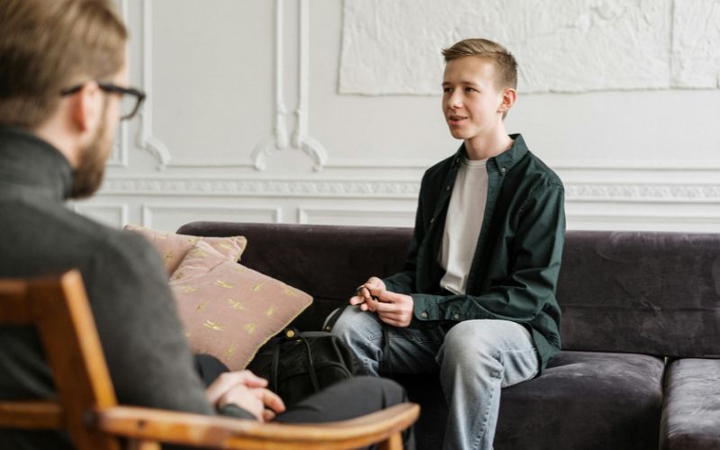 Teen talking with therapist during CBT therapy session.