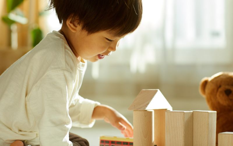 Child focused while building blocks in warm light.