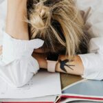 Person stressed with head down on desk studying.