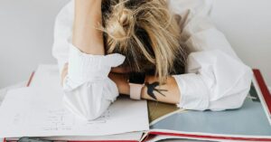 Person stressed with head down on desk studying.