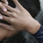 Man sitting with hands on neck, conveying a sense of worry and depression.